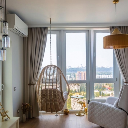 Cozy reading nook with a rattan hanging chair and floor-to-ceiling city views
