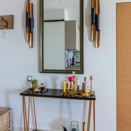 Entryway console table with mirror, wall sconces, and brass decor accents