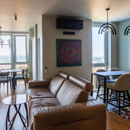 Living room corner with leather sofa, abstract artwork, and panoramic city views