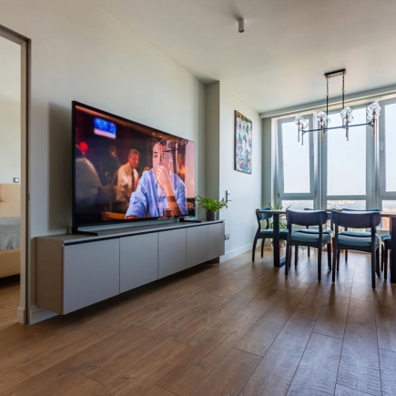 Media wall with wall-mounted TV, floating cabinet, and dining area beyond