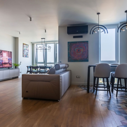 Open living and dining area with leather sofa, abstract art, and bar-height dining table