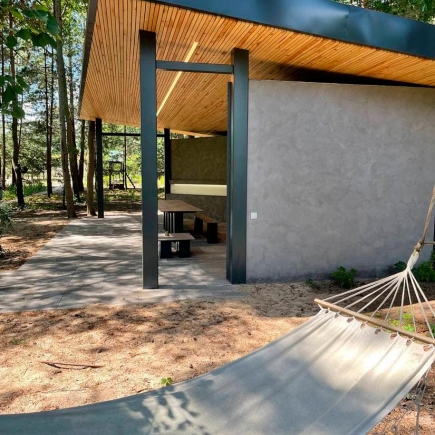 Pavilion exterior with a hammock strung between trees in the foreground