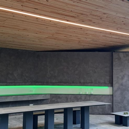 Pavilion interior lit by a green LED strip along the concrete bench wall