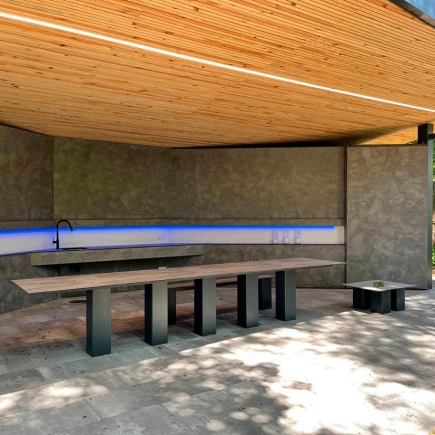 Pavilion interior with integrated sink lit by a blue LED strip and built-in concrete table