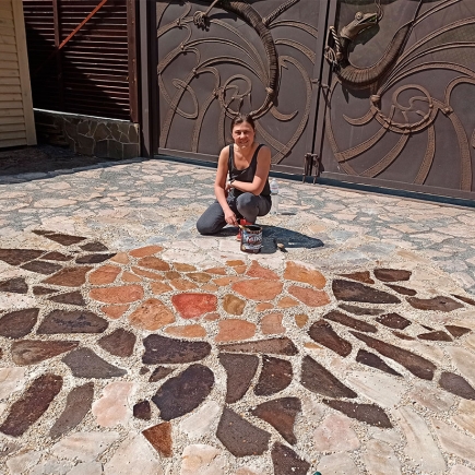 Artisan hand-painting a decorative stone medallion into the driveway paving