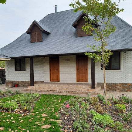 Blossoming catalpa tree branch framing the white cottage and slate roof
