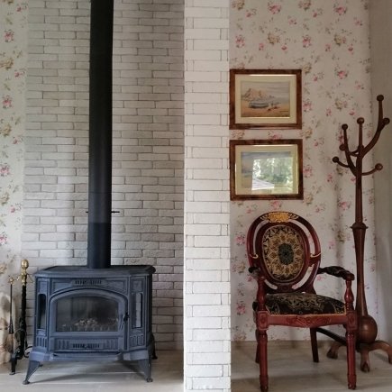 Classic sitting room with a black wood-burning stove, floral wallpaper, and antique armchair