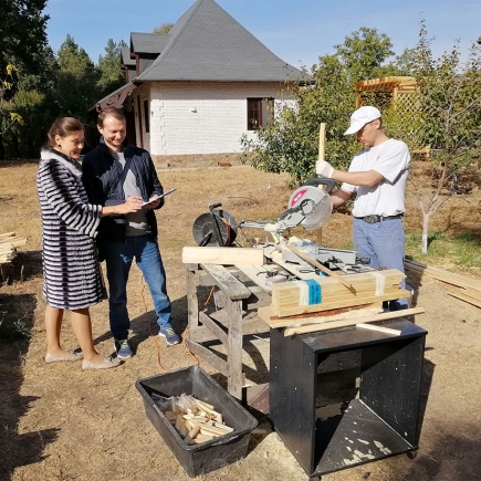 Contractor and homeowners consulting beside the workshop table while wood is cut for the pergola