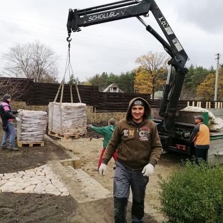 Crane truck delivering pallets of stone paving to the garden site