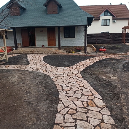 Curved flagstone pathway under construction in front of the property during landscaping