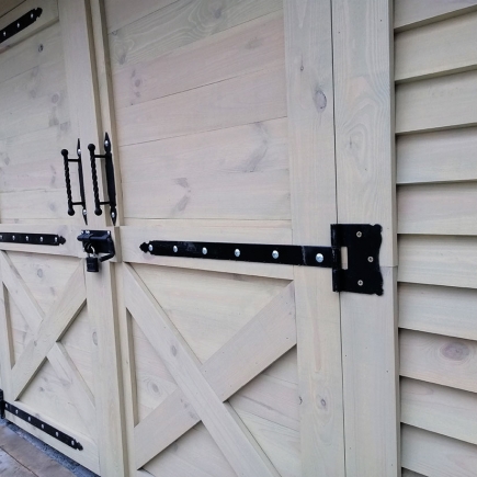 Detail of the wrought iron strap hinges on the timber shed's barn doors