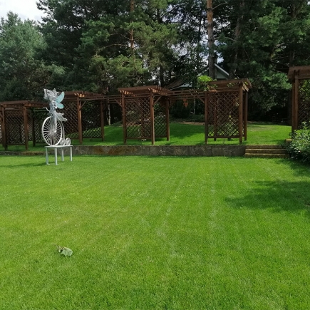 Fairy-on-bicycle sculpture on the lawn with the pergola row in the background