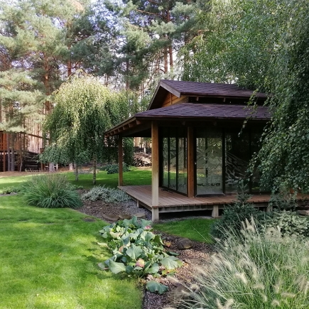 Glass pavilion terrace framed by weeping willow and hostas