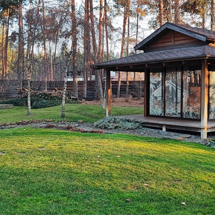 Glass-walled garden pavilion nestled among pine trees and white birches