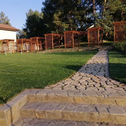 Stone steps leading up to the pergola-lined lawn at golden hour