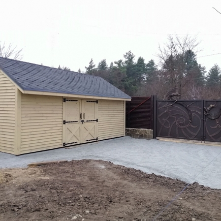 Timber storage shed with barn-style doors beside the wrought iron entrance gate