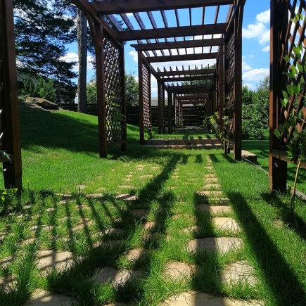 Workers laying flagstone paving beneath the pergola framework