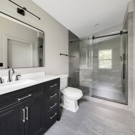 Bathroom with black wood vanity, marble counter, and glass-enclosed walk-in shower