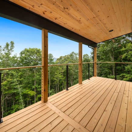 Covered deck with wood ceiling, timber posts, and cable railing framing the mountain view