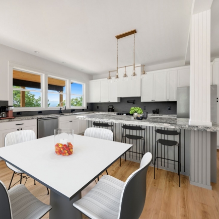 Kitchen with white cabinetry, granite island, and pendant lighting over the dining table