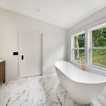 Primary bathroom with freestanding soaking tub, marble floor, and window view