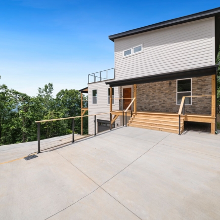 Rear exterior with covered entry, wood steps, and concrete patio