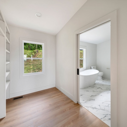 Walk-in closet hallway leading to the primary bathroom with freestanding tub