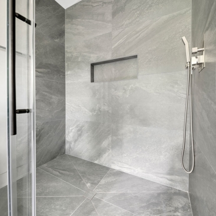 Walk-in shower detail with tiled niche and handheld showerhead