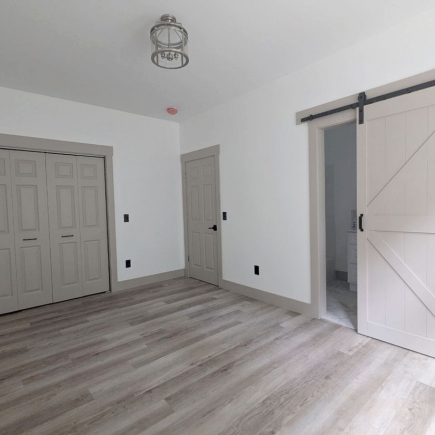 Bedroom with double closet and sliding barn door leading to an en-suite bathroom