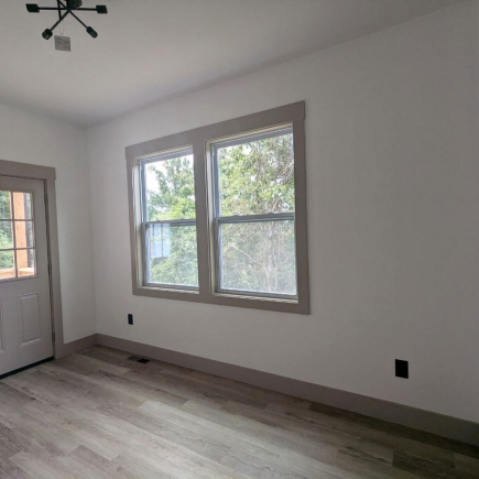 Bedroom with double window overlooking trees and doorway to the entry hall