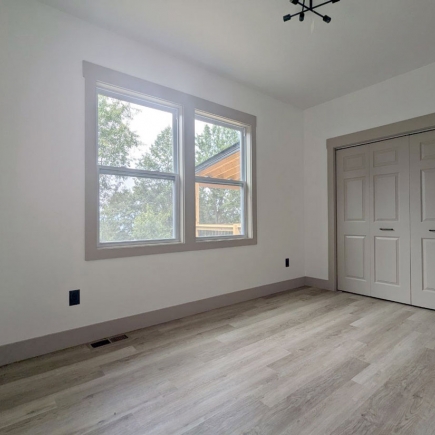 Bedroom with window view of the neighboring home and a double closet