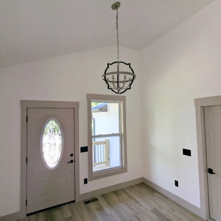 Entryway with vaulted ceiling, statement pendant light, and glass-paneled front door