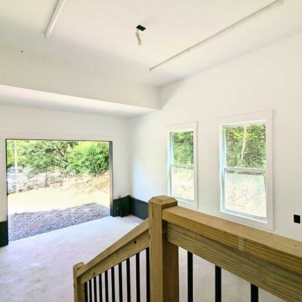 Garage interior with open bay door and wood loft railing above