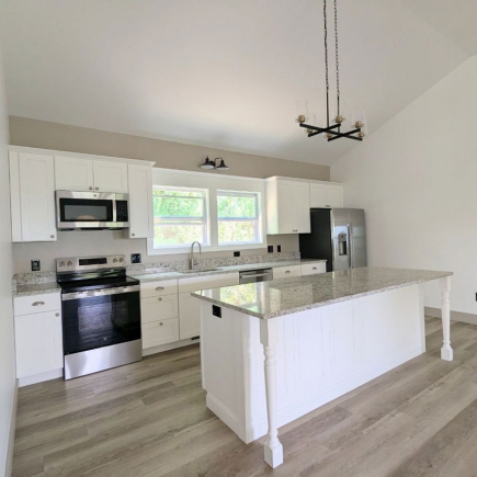 Kitchen with white cabinetry, stainless appliances, and a granite island