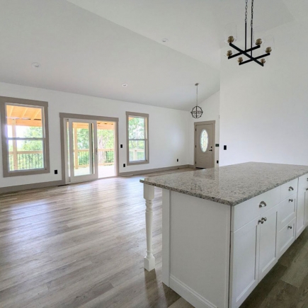 Open-concept kitchen island and living area with vaulted ceiling and natural light
