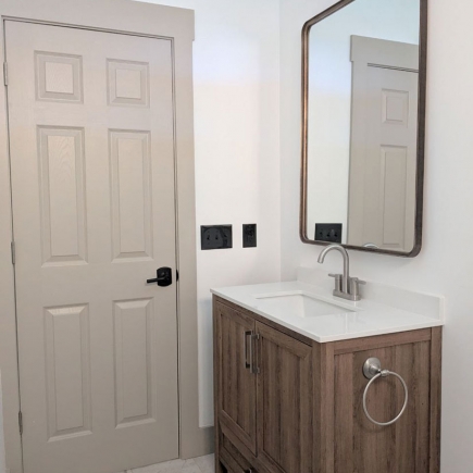 Powder room with wood vanity, framed mirror, and towel ring