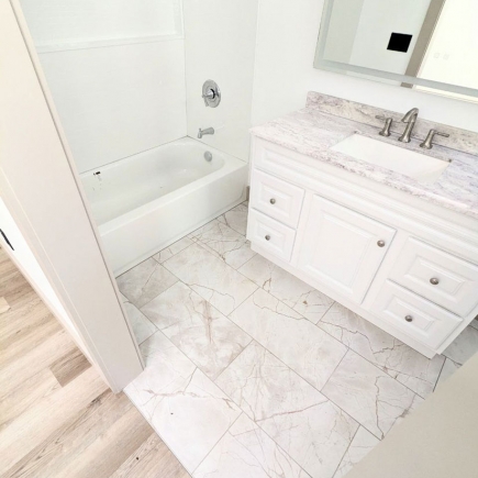 Primary bathroom with soaking tub, marble-tiled floor, and vanity