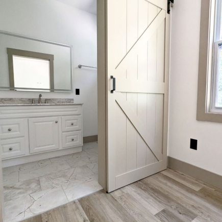 Sliding barn door opening into a bathroom with vanity and marble-tiled floor