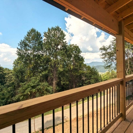 View from the covered porch railing looking out over the treeline toward the mountains