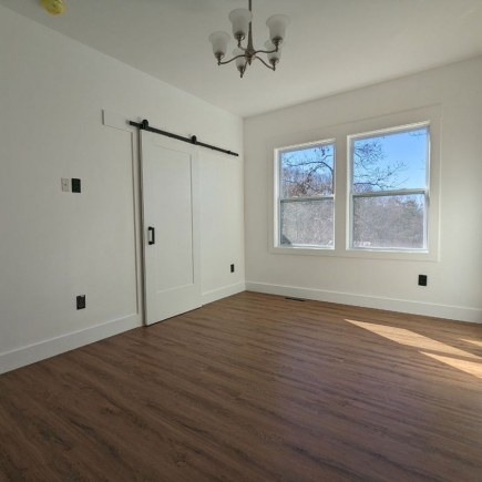 Bedroom with sliding barn-door closet and a winter tree-line view