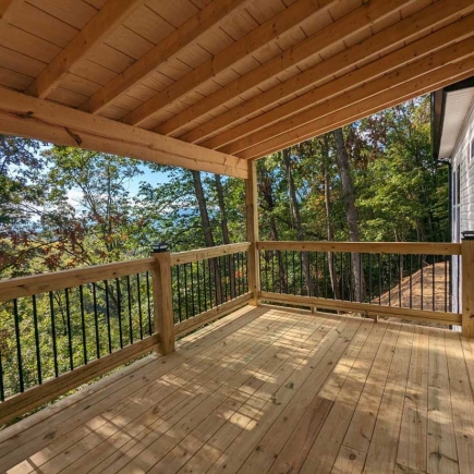 Covered back deck with cable railing and mountain view through the trees