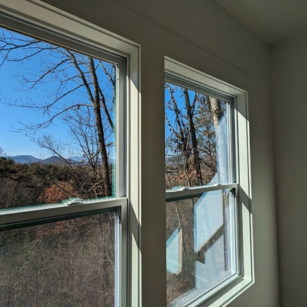 Winter view of bare trees and distant mountains through a bedroom window
