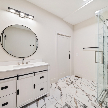 Bathroom with round mirror, sliding barn-door vanity, and marble-tiled floor
