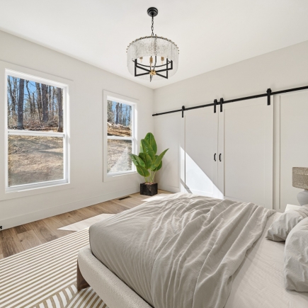 Bedroom with statement chandelier, sliding barn-door closet, and wooded view