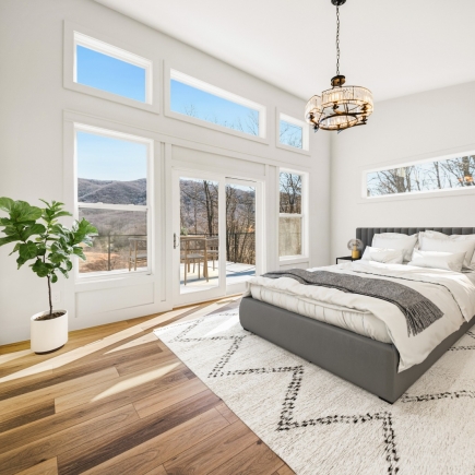 Bedroom with vaulted ceiling, tall mountain-view windows, and deck access