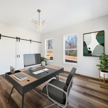 Home office with sliding barn doors, desk, and framed artwork