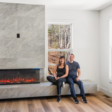 Homeowners relaxing on the stone hearth bench beside the linear fireplace