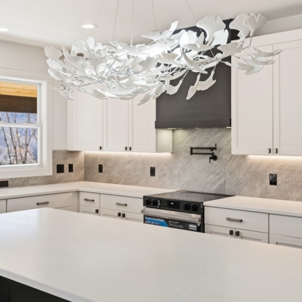 Kitchen island, range, and sculptural chandelier with marble backsplash