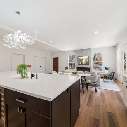 Kitchen island with sculptural chandelier, dining area and living room beyond