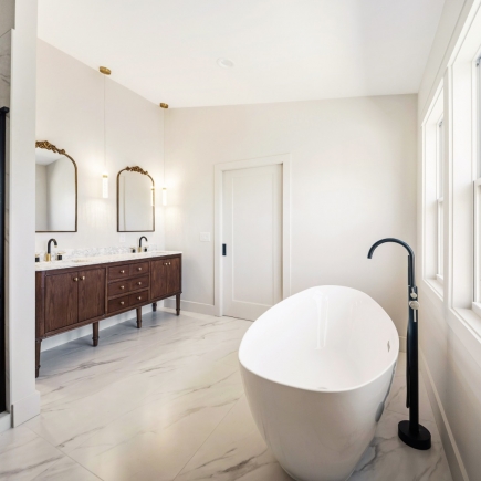 Primary bathroom with freestanding soaking tub and dark wood double vanity
